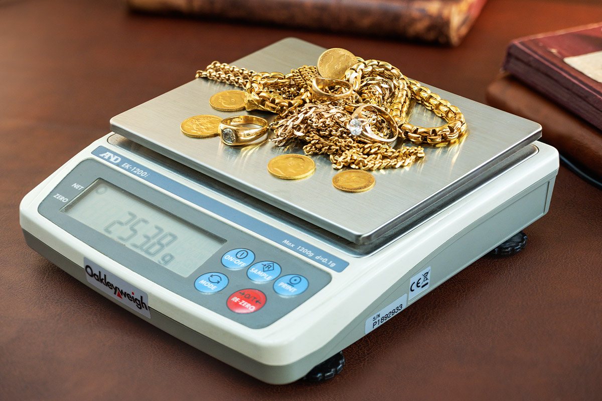 Gold jewelry and coins being weighed on a certified scale